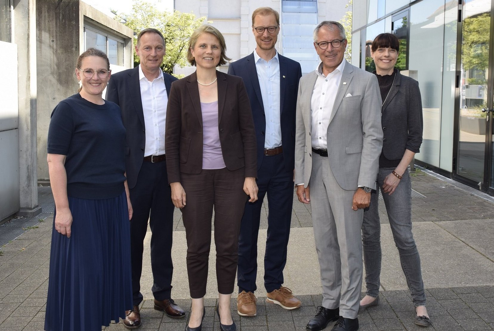 Sechs Männer und Frauen stehen auf dem Campus der Hochschule