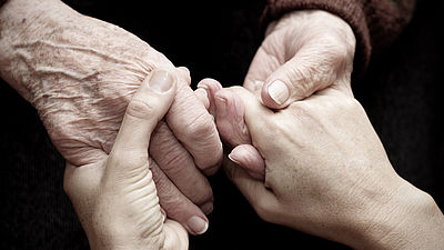 Zwei Paar sich haltender Hände der älteren und jüngeren Generation