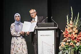 Mann überreicht einer Studentin eine Auszeichnung bei der Graduiertenfeier der Hochschule Esslingen