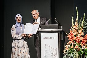 Mann überreicht einer Studentin eine Auszeichnung bei der Graduiertenfeier der Hochschule Esslingen