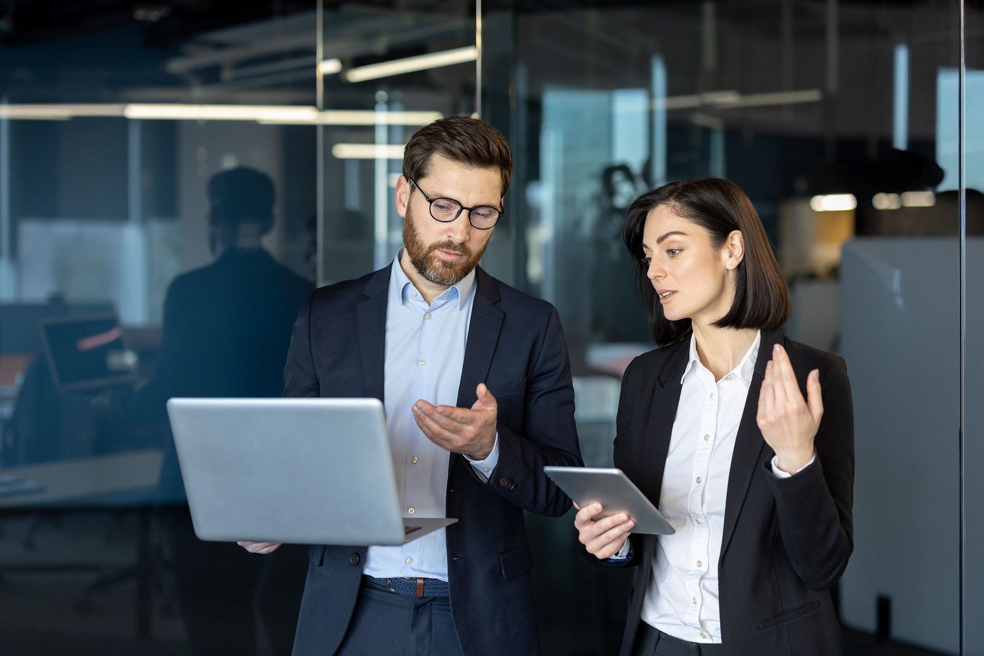 Mann und Frau sprechen miteinander und halten ein Laptop in der Hand