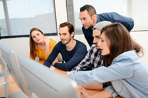 group of five young people student with teacher in computer school classroom learning programming with desktop computer in a row