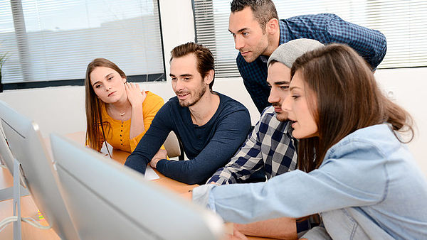 group of five young people student with teacher in computer school classroom learning programming with desktop computer in a row