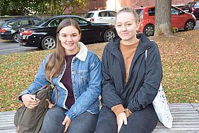 Zwei junge Frauen sitzen auf einer Bank