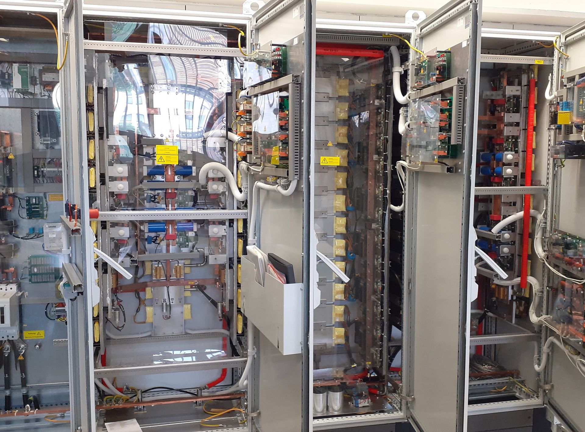 Drei große Schränke mit elektrischen Geräten und Kabeln darin. 