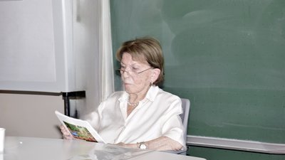 Eine Frau sitzt an einem Tisch und liest etwas vor