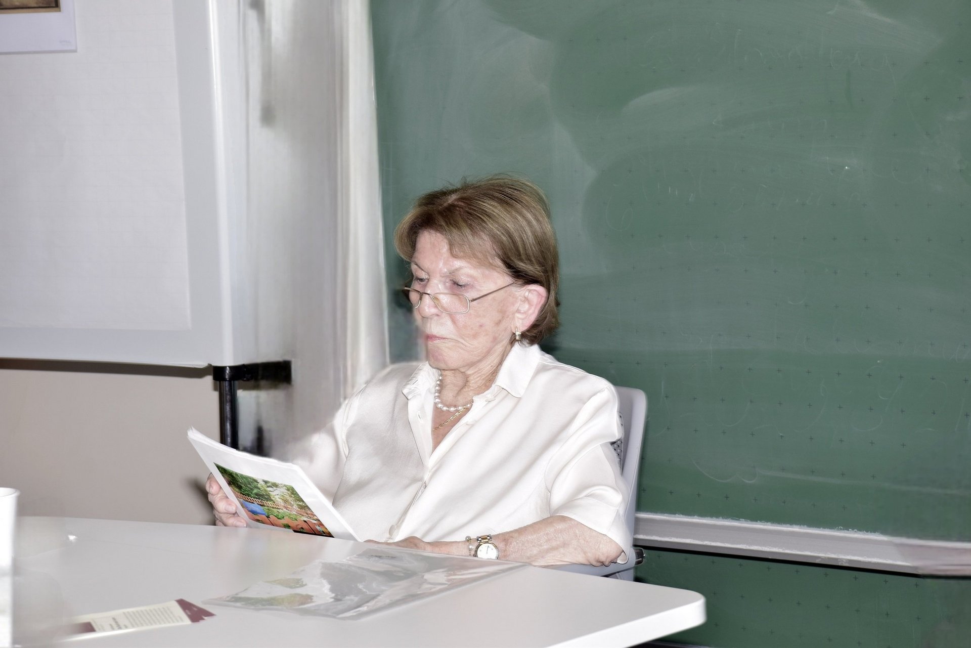 Eine Frau sitzt an einem Tisch und liest etwas vor