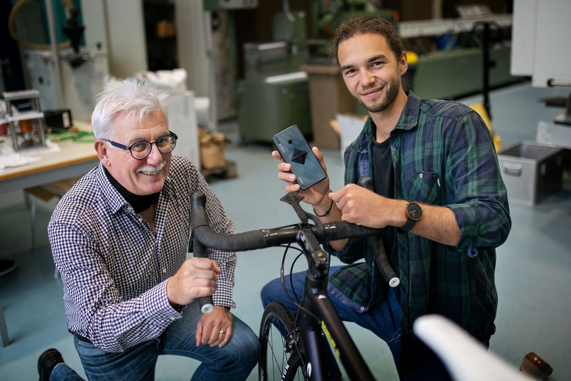 Zwei Männer knien an einem Fahrrad