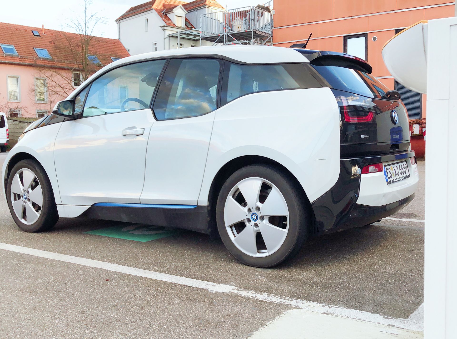 Ein schwarz-weißes Elektro-Auto vor einer Ladesäule.