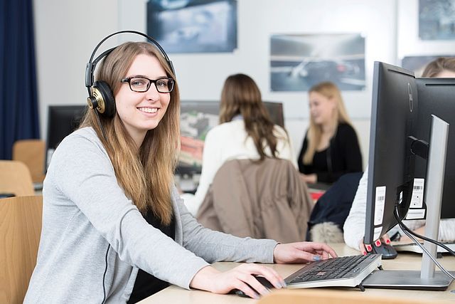 Studentin mit Kopfhörer vor dem Computer