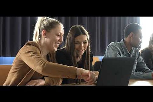 Zwei Frauen vor einem Laptop. Die Frau links im Bild zeigt der anderen etwas auf dem Bildschirm.