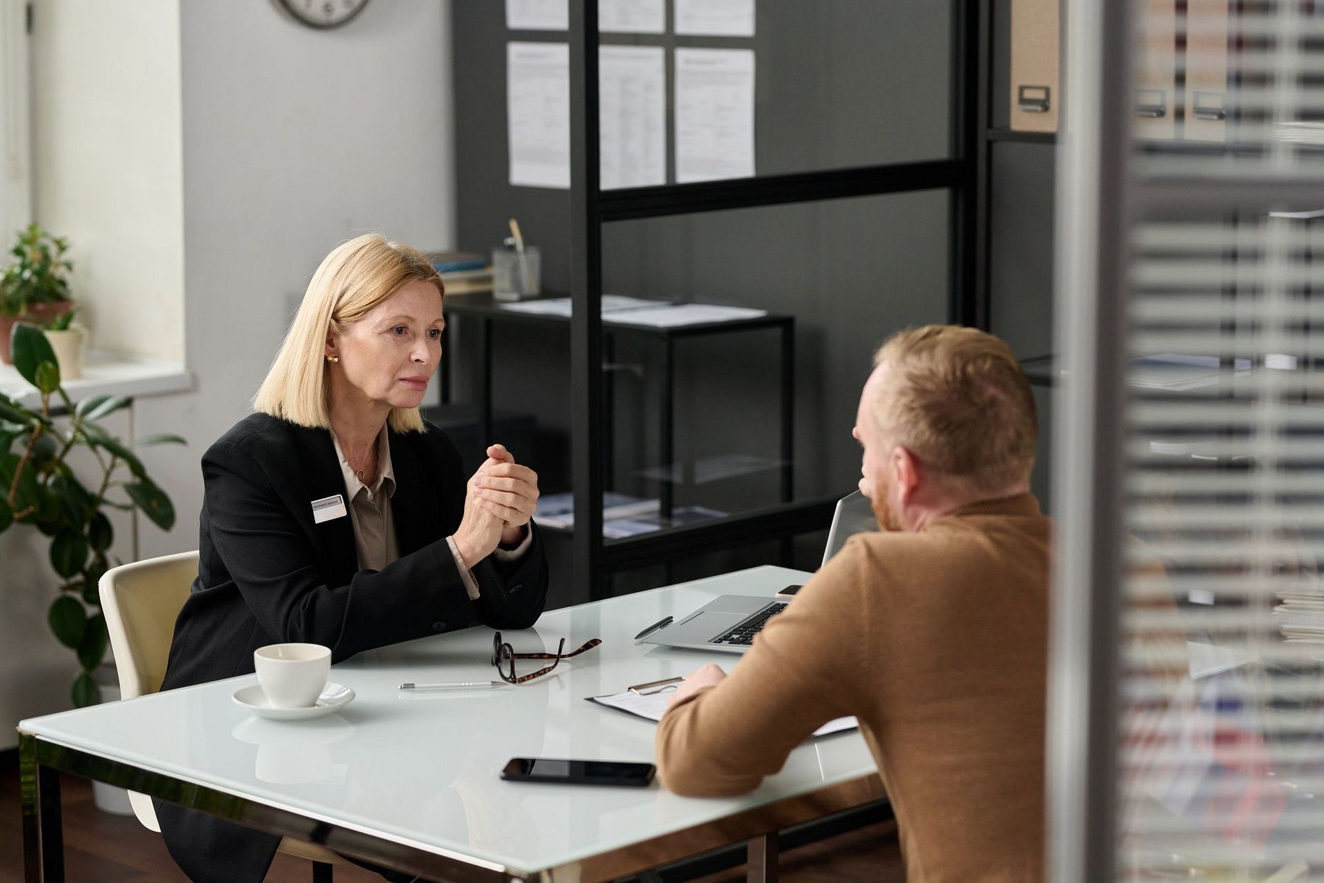 Portrait of caring social worker consulting man behind glass wall in office