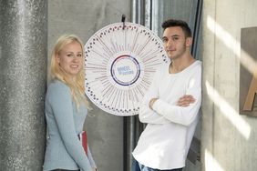 Eine junge Frau und ein junger Mann an einem Glücksrad