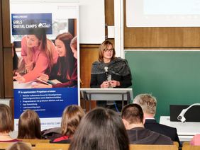 Frau steht am Rednerpult in einem Vorlesungssaal