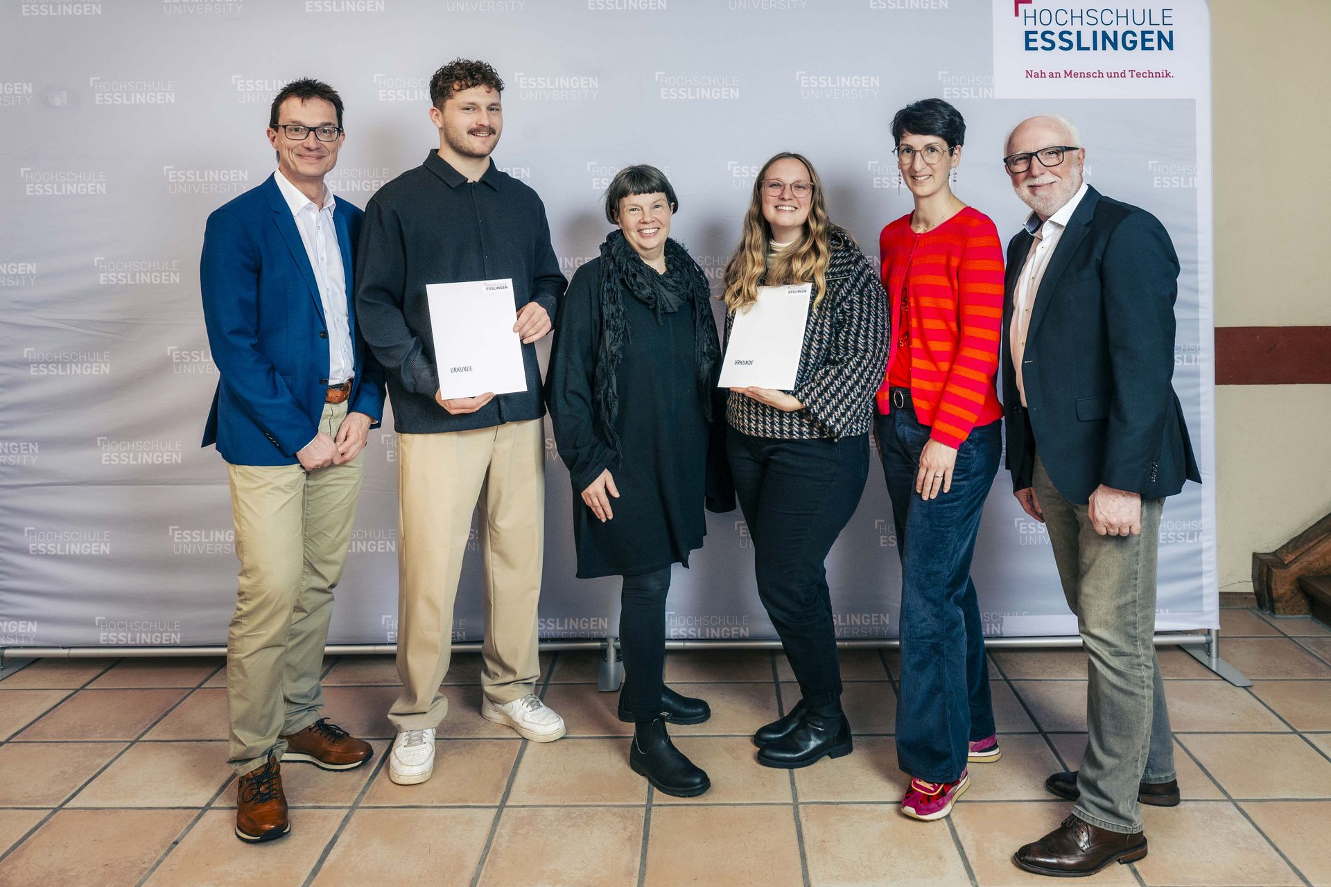 Gruppenfoto mit Männern und Frauen - zwei davon halten eine Urkunde in der Hand
