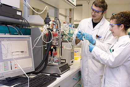 Zwei Studierende entnehmen eine Probe aus dem Bioreaktor 