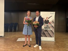 Mann und Frau mit Blumenstrauß stehen auf einer Bühne