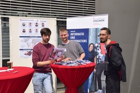 Drei Männer an einem Infostand