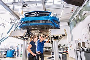 two person looking at a car under a lifting platform