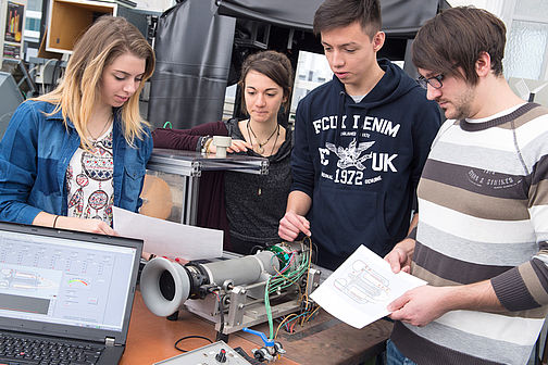 Two young women and two young men look at a project setup.