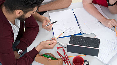 Studierendengruppe lernen Mathe am Tisch- Sicht von oben 