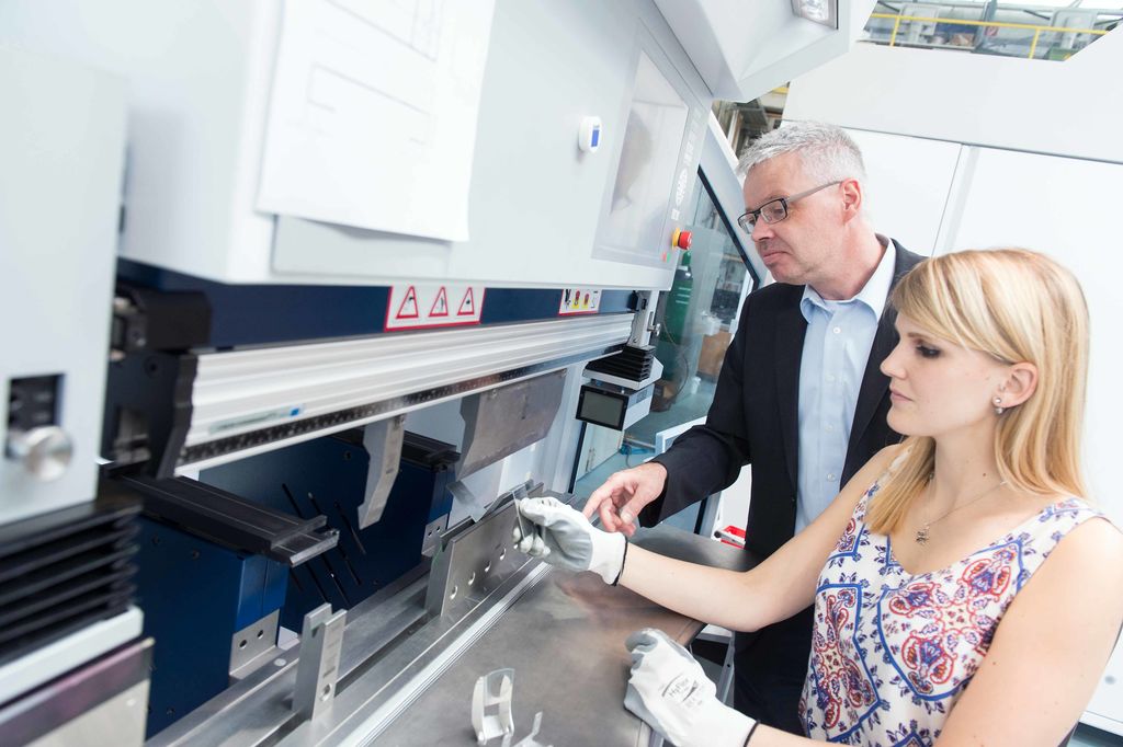 Studentin des Studiengangs Maschinenbau mit einem Professor vor einem Laborgerät