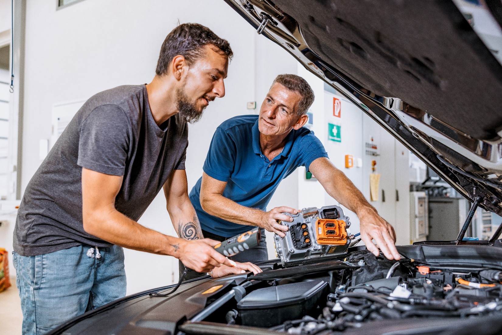 Zwei Männer beugen sich über den Motorraum eines Autos