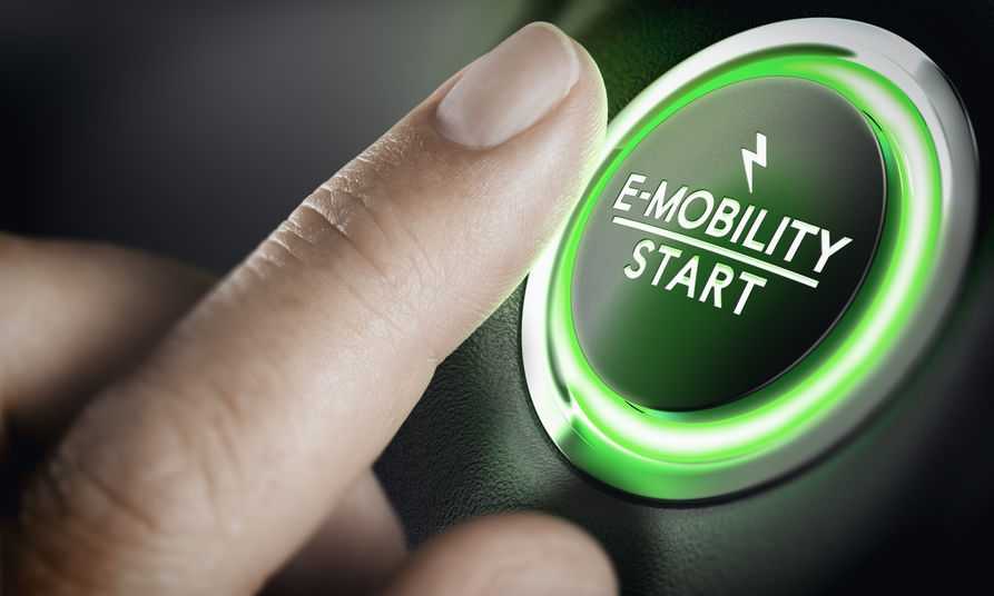 Finger drückt auf einen grünen Knopf mit Aufschrift E-Mobility