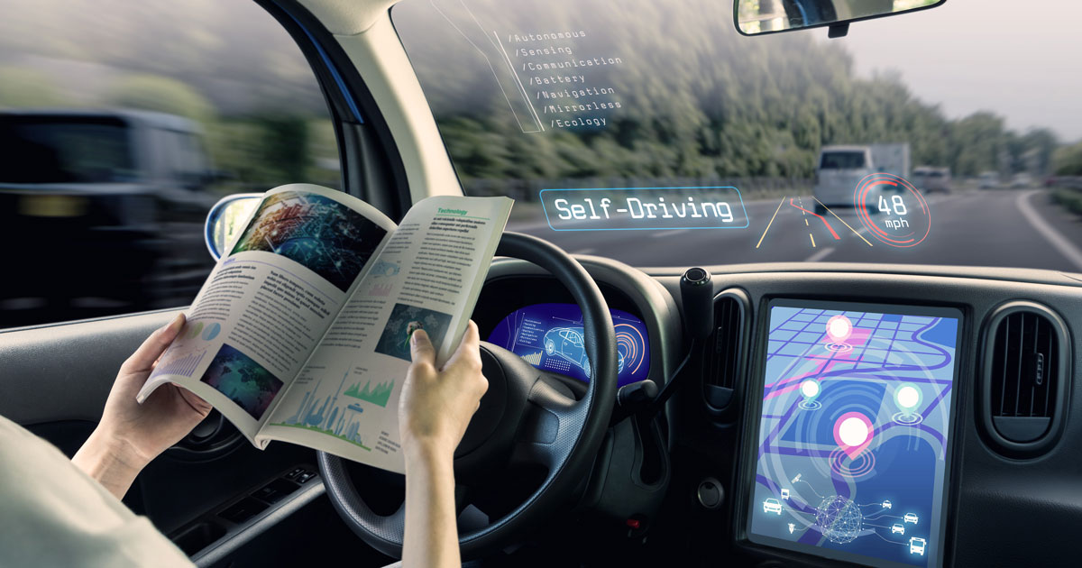 Eine Person sitzt in einem autonom fahrenden Auto und liest in einem Heft.