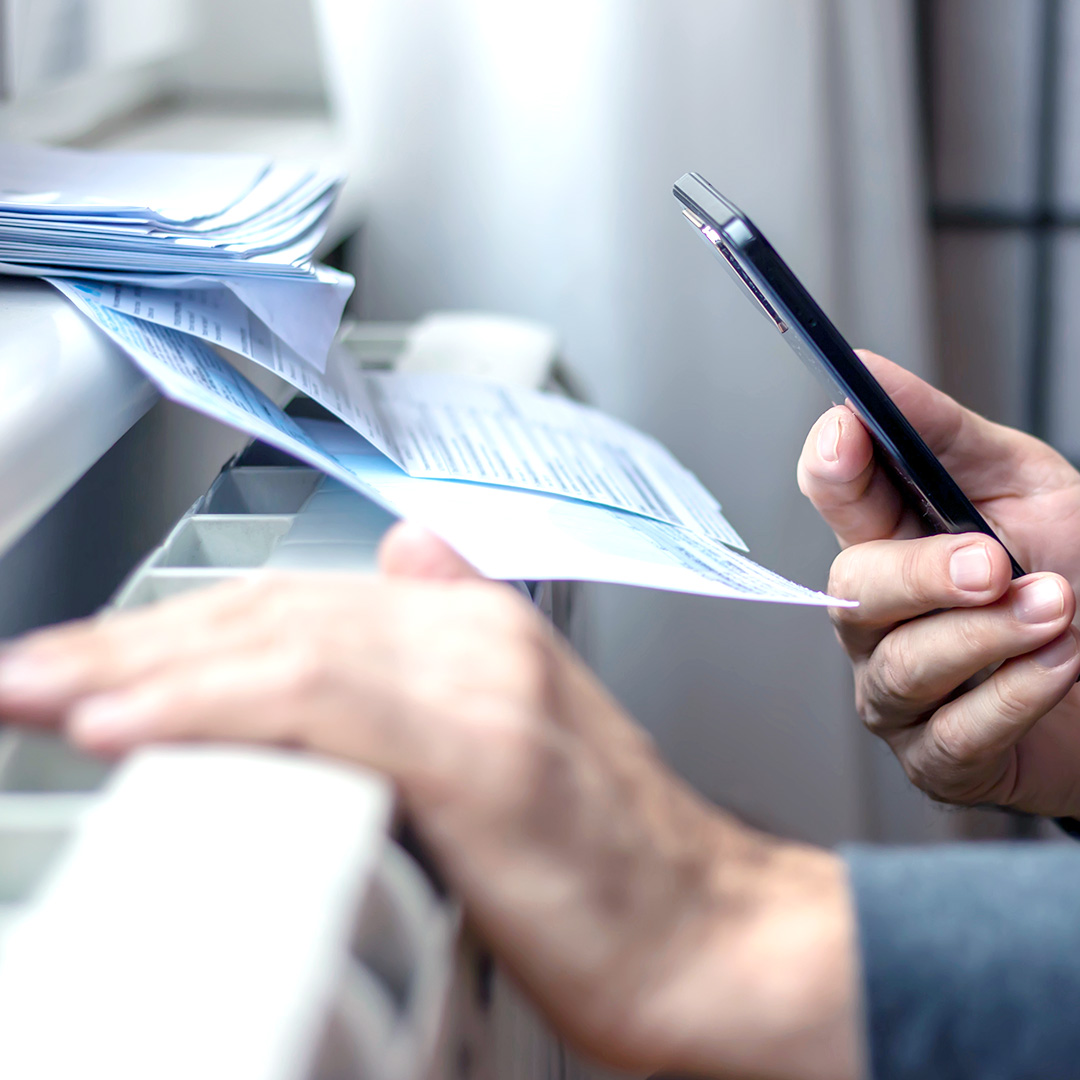 Eine Hand mit Smartphone und Dokumenten