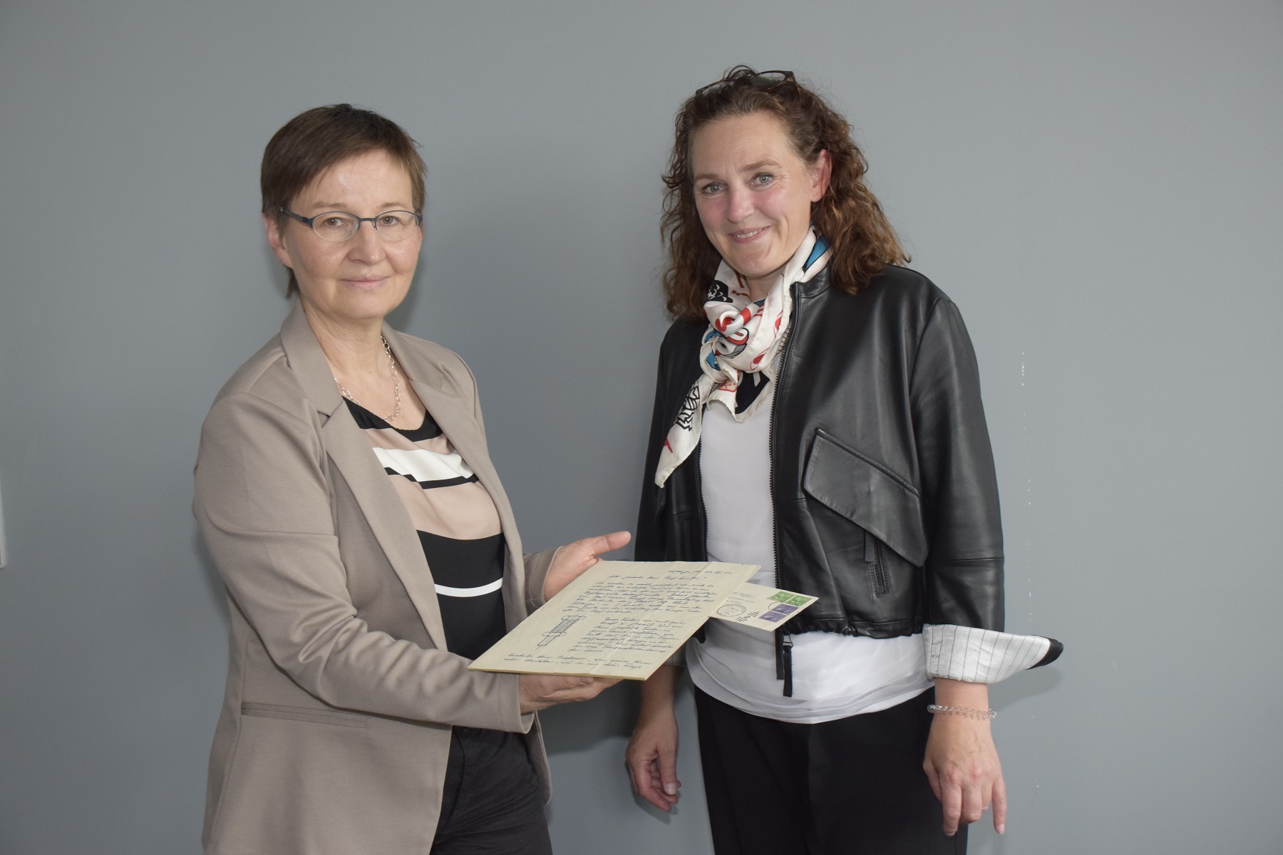 Zwei Frauen halten ein historisches Dokument in der Hand