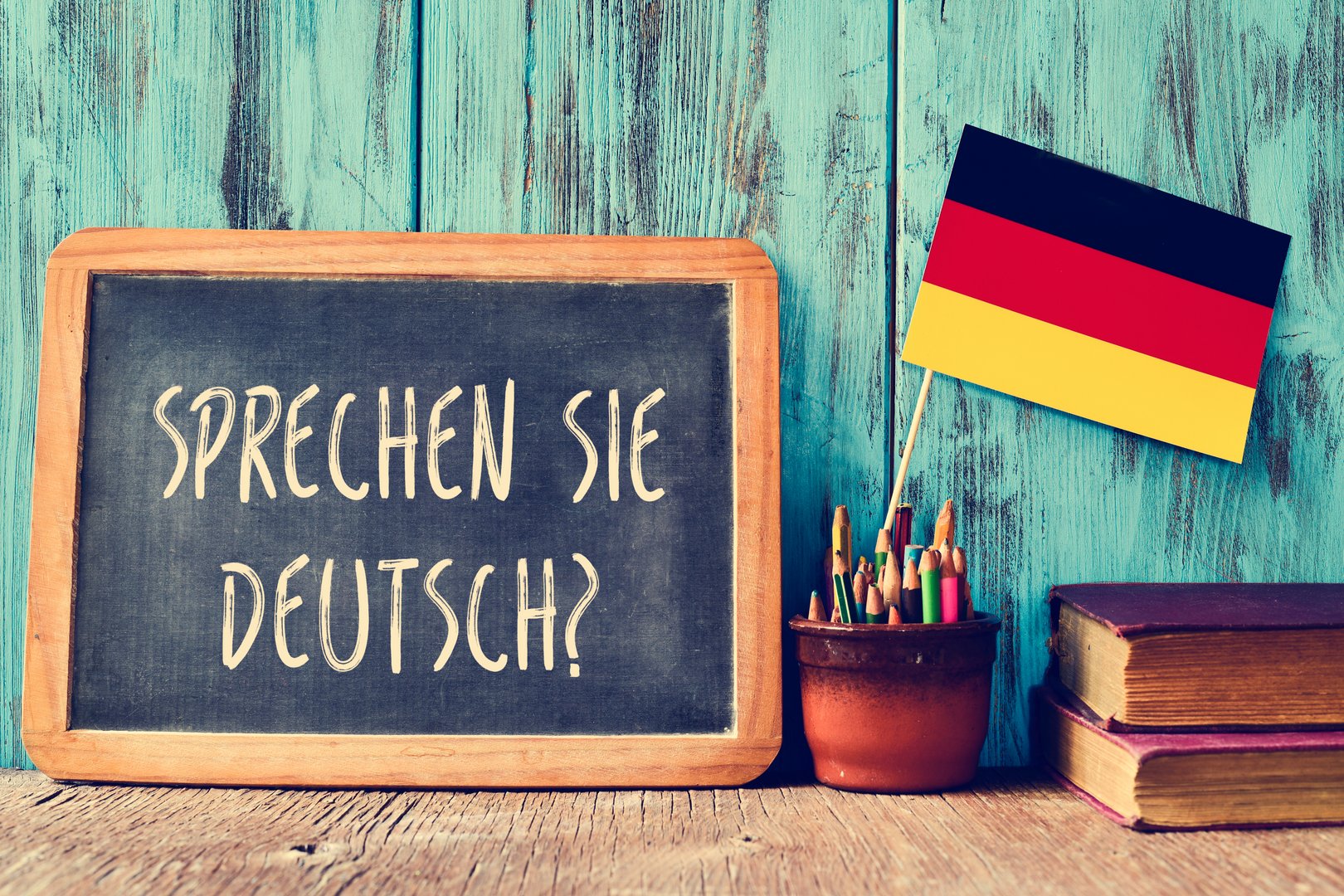 Auf einer kleinen Tafel steht "Sprechen Sie Deutsch", daneben sind Stifte und eine kleine deutsche Flagge