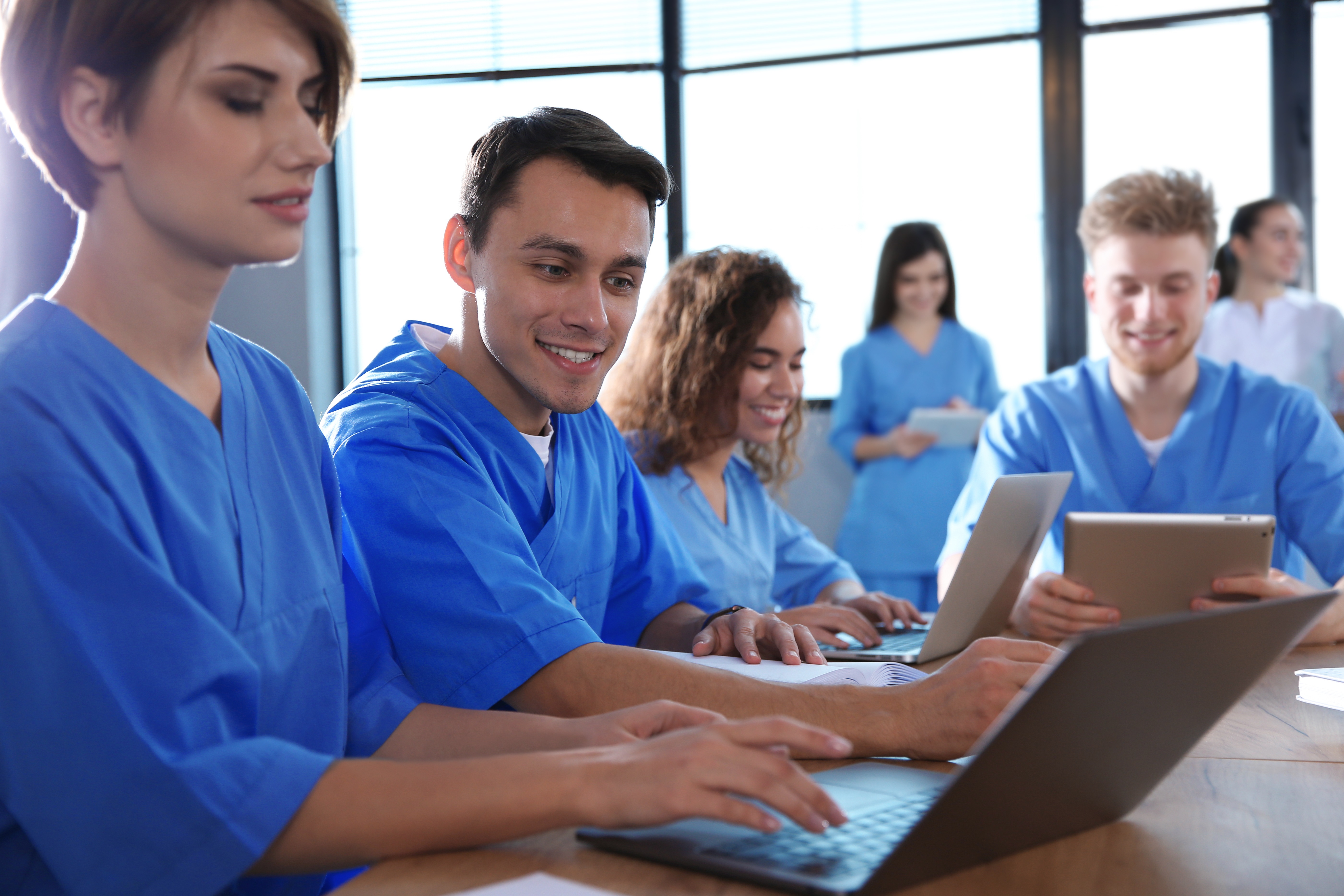 Pflegestudenten sitzen im Seminarraum vor Laptops